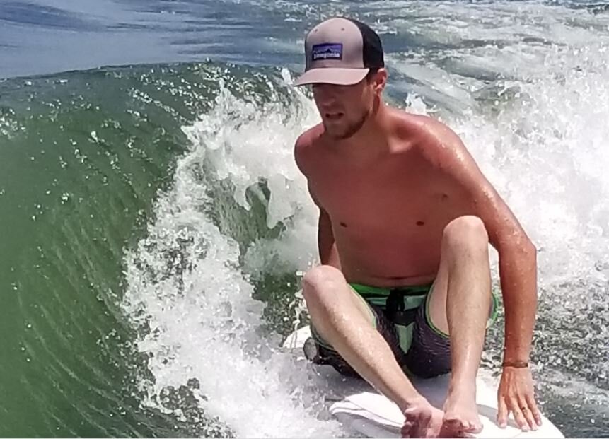 guy with hat sitting on surfboard