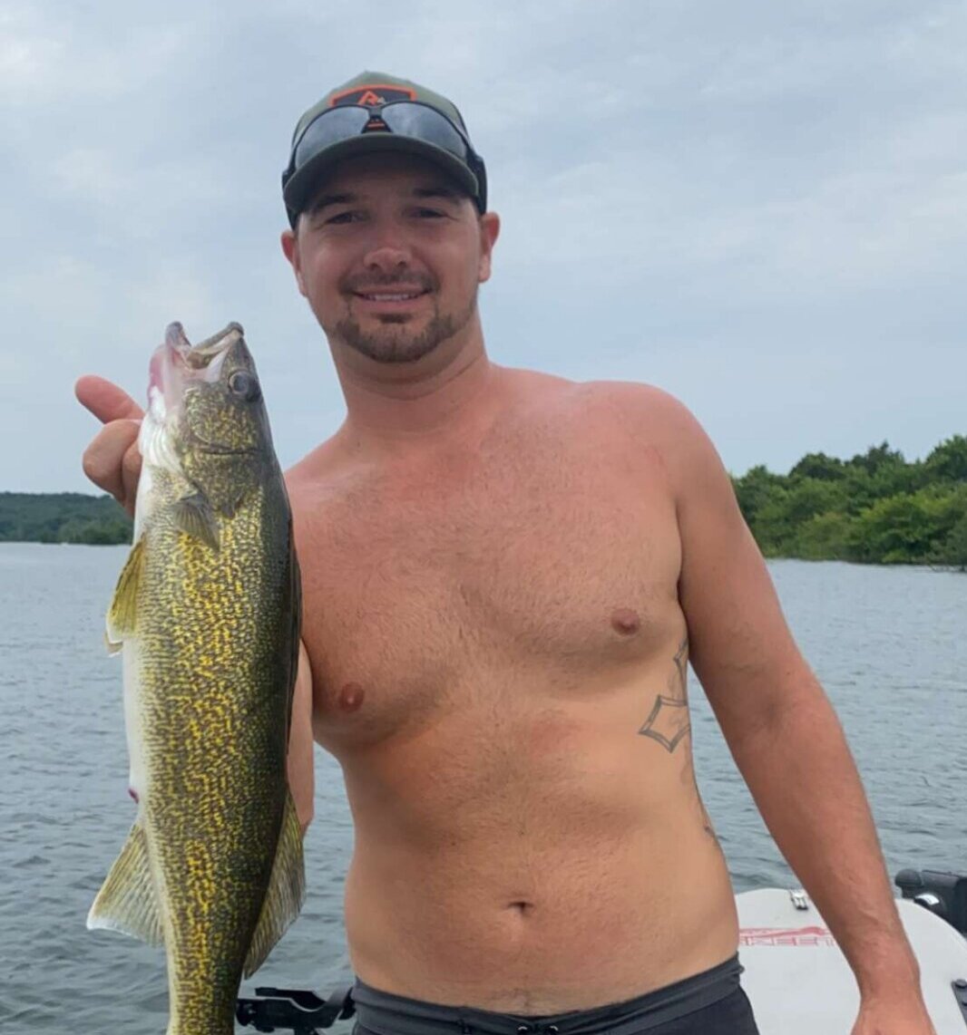 guy holding up fish on boat